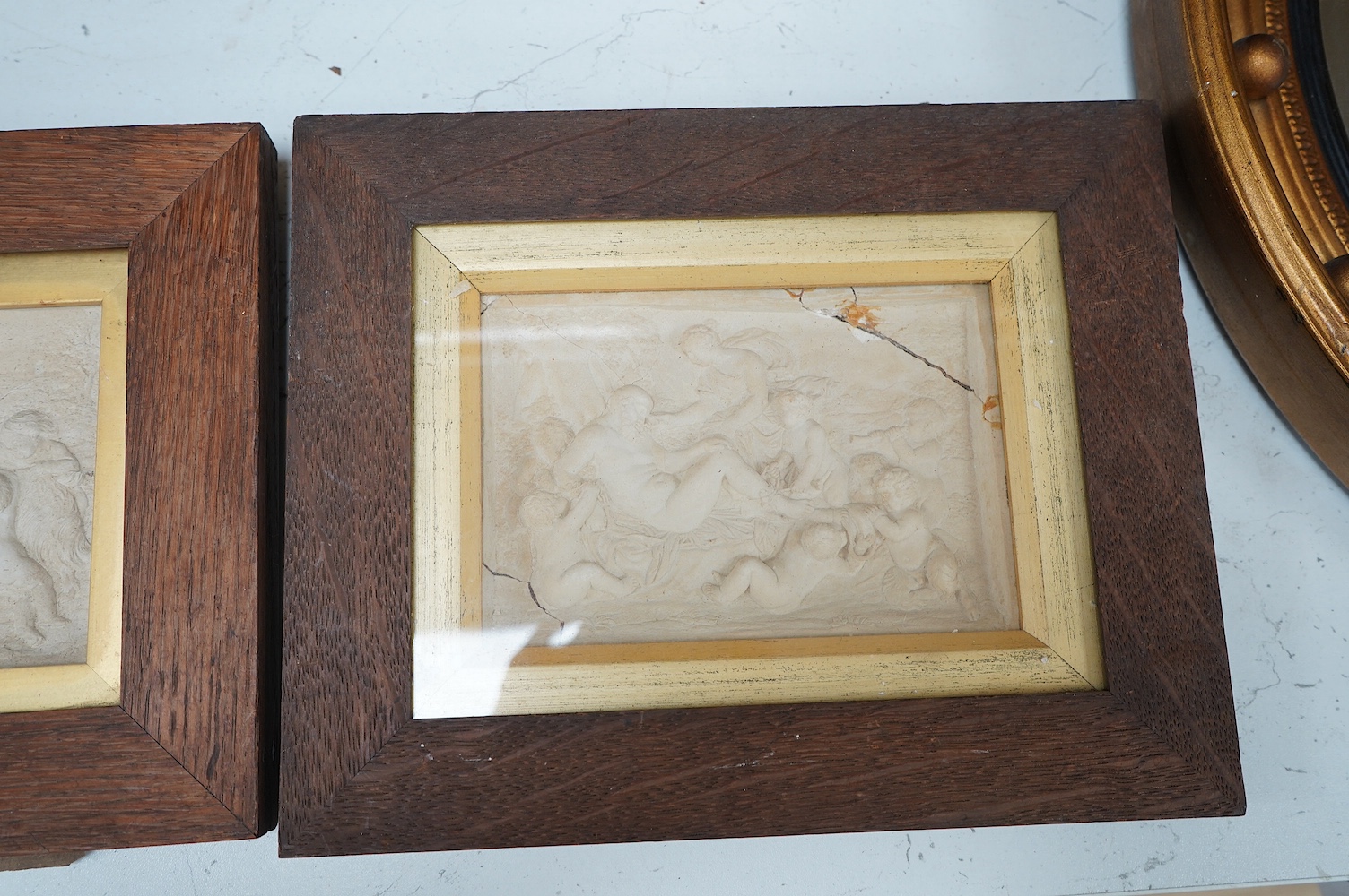 Three plaster relief panels depicting putti, framed, 21 x 25cm. Condition - two fair, one damaged